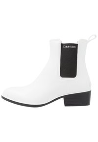Botas Chelsea blancas con un acabado suave, panel lateral elástico en negro y un tacón bajo apilado. Logo visible en el elástico.