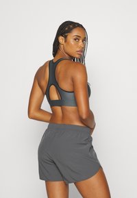 Sportieve grijze sportbeha met een racerback-ontwerp en uitsnijdetails, gecombineerd met bijpassende grijze shorts met een elastische tailleband.
