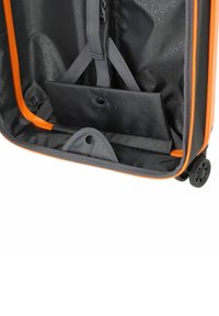 Offener schwarzer Koffer mit orangefarbenen Rädern, der die Innenräume mit Trägern und eine kleine Klapptasche mit Druckknopfverschluss zeigt.