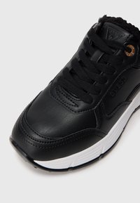 Czarne skórzane sneakersy z teksturowaną powierzchnią, okrągłymi sznurówkami, szytymi detalami i białą gumową podeszwą z lekkim obcasem. Złote akcenty.