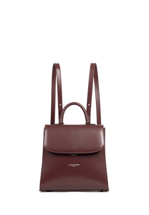 Sac à dos structuré en cuir bourgogne avec une anse supérieure, deux bretelles ajustables et une fermeture à rabat. Présente un logo sur le devant.