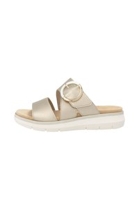 Beige leather sandal with two wide straps and a circular gold accent. Textured finish, cushioned insole, and white platform sole.