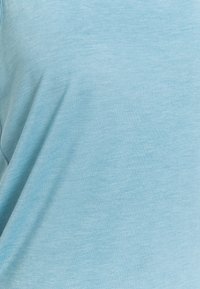 Ljusblå t-shirt i mjukt, andningsbart tyg med en jämn yta och avslappnad passform, med subtila färgvariationer.