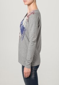 Graues Langarmshirt mit buntem abstraktem Druck auf der Vorderseite, aus weichem Material, im entspannten Schnitt und mit einfachem Design.