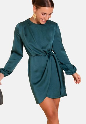 Vestido de satén verde azulado con mangas abullonadas largas, detalle de cinturilla atada y una falda ligeramente drapeada. Textura suave, hasta la rodilla, diseño minimalista.