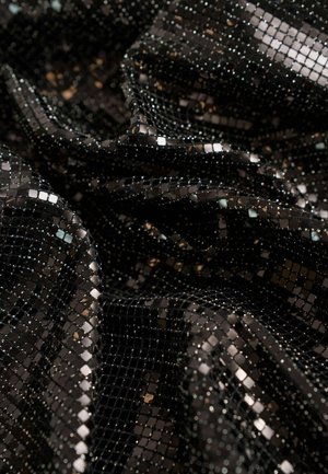 Zwarte paillettenstof met kleine, reflecterende vierkanten, wat een gestructureerd, glanzend oppervlak creëert. Het materiaal is lichtgewicht en valt gemakkelijk.