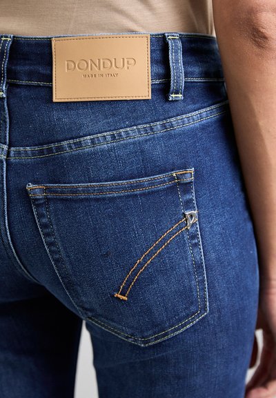 Tmavomodré džíny z denimu s koženou nášivkou na páse, kontrastným žltým prešívaním a jedinečným dizajnom zadnej vrecka.
