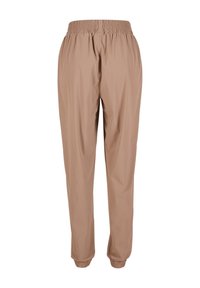 Pantalons beige à cordon de serrage avec taille élastique, jambes fuselées et poignets élastiques ; tissu lisse et léger sans motifs ni accents visibles.