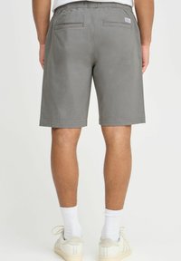 Gray shorts with an elastic waistband, two back pockets, and a straight cut. Material appears soft with a smooth texture.