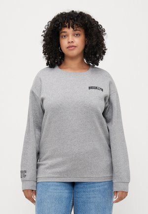 Grå sweatshirt med rund halsringning och neddragna axlar. Har texten "BROOKLYN" på bröstet och "NYC" på ärmen. Mjuk tyg.
