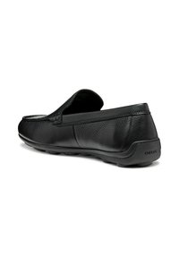 Scarpa nera in pelle slip-on con punta arrotondata, finitura testurizzata e suola in gomma. Presenta cuciture sottili e un logo "GEOX" sul tallone.
