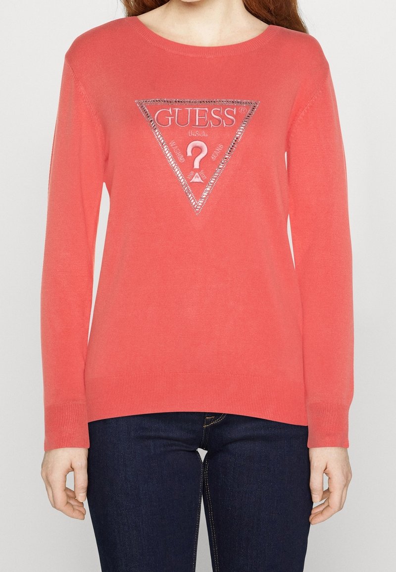 Maglione color corallo realizzato in tessuto morbido con maniche lunghe, scollo rotondo e un dettaglio triangolare con logo argentato sul petto.