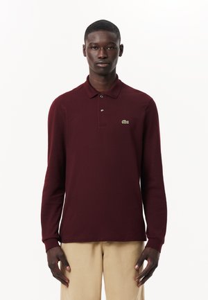 Polo shirt bordeaux a maniche lunghe con colletto, dotato di tre bottoni e un logo ricamato verde sulla parte sinistra del petto.