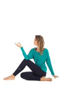 Türkises Langarmoberteil und marinefarbene Leggings. Weiches Material, lässiger Schnitt und dezenter Logoaufdruck am Bein. Barfuß im Sitzposition.