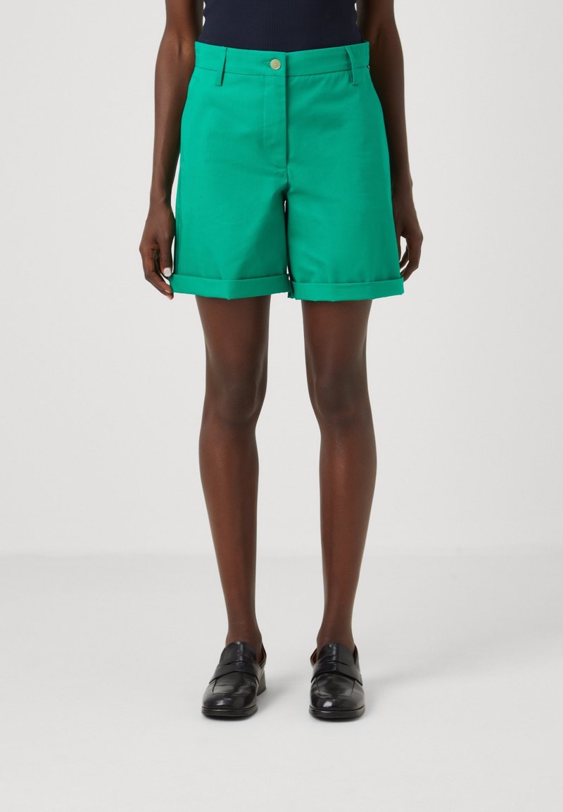 Grüne Shorts aus einem glatten Stoff mit tailliertem Schnitt, ausgestattet mit umgeschlagenem Saum, frontalen Taschen und einem einzigen Knopfverschluss.