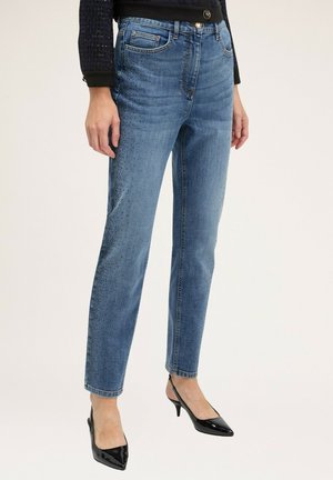 Lichtblauwe denim jeans met een rechte pijp, voorzien van een vervaagde wassing en stippenversieringen aan één kant. Draag met glanzende zwarte hakken.