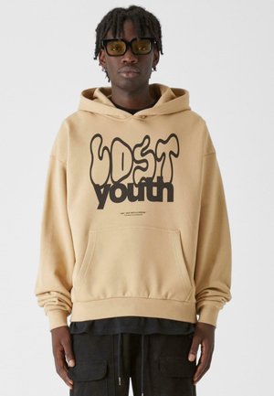 Beige hættetrøje lavet af blødt stof med frontlomme og ribbede manchetter. Har fed sort tekst "LOST youth" og yderligere tekst nær lommen.