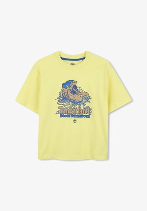 T-shirt en coton jaune avec un motif bleu de bottes et le texte "Timberland Boots With Roots." Manches courtes et coupe décontractée.