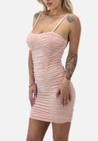 Ribbad, åtsittande miniklänning i mjukt rosa med justerbara band och rynkad textur för en figurnära silhuett.