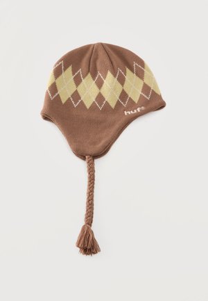 Bonnet marron en maille avec cache-oreilles, motif à losanges crème, liens tressés, pompon et petit logo, sur un fond uni.