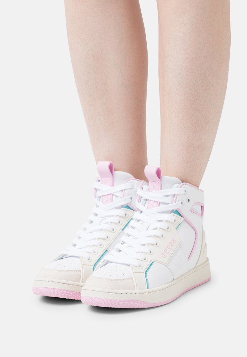Witte hoge sneakers met roze zolen en accenten, gedragen op blote benen tegen een effen witte achtergrond.