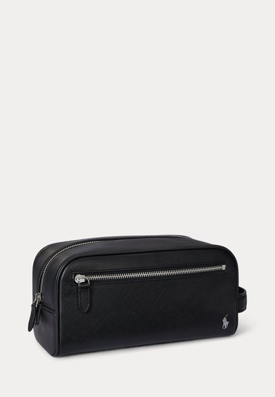 Μαύρη ορθογώνια τσαντούλα καλλυντικών με υφή, εμπρόσθια τσέπη με φερμουάρ, πλευρική λαβή και ασημένιο κεντημένο λογότυπο κάτω δεξιά.