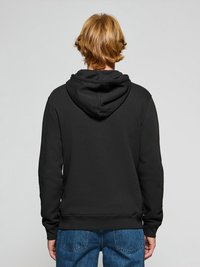 Svart huvtröja med bakficka och justerbar dragsko i huvan, med ribbad mudd och nederkant, tillsammans med blå jeans.