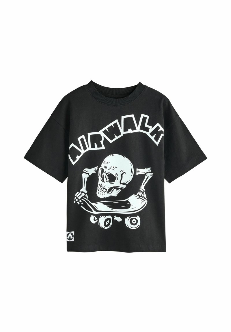 T-shirt nera in cotone con una grafica bianca di un teschio su uno skateboard, con il testo "AIRWALK" in grassetto e in lettere arcuate sopra.