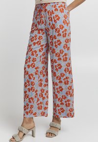 Flödande, lätta byxor i tyg med blå bakgrund, prydda med ett blommönster i rött och grönt. Elastisk midja med dragsko.