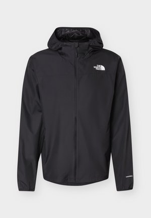 Must kapuutsiga tuulekindel jope esilukuga, elastsete varrukasäärtega, The North Face'i logoga rinnal ja WindWall tekstiga varrukal.