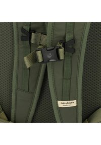 Tirantes de mochila verdes hechos de tela de malla con clips ajustables y correas. Presenta una etiqueta que dice “FJÄLLRÄVEN Suecia 1960.”