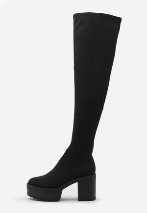 Botte noire cuissarde avec talon bloc et semelle plateforme, dessus en tissu lisse, profil latéral sur fond blanc.