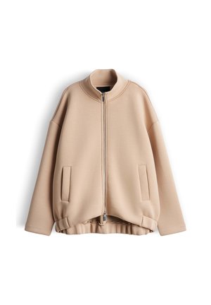 Beige Reißverschlussjacke mit hohem Kragen, elastischem Saum, langen Ärmeln und zwei Fronttaschen, auf weißem Hintergrund dargestellt.