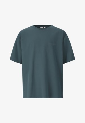T-shirt oversize à manches courtes bleu sarcelle foncé avec col rond et texte subtil "LES ARCS" sur la poitrine gauche.