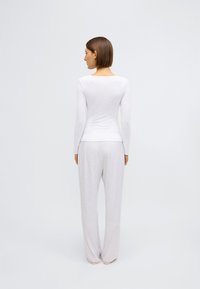 Svetlosivá košeľa s dlhým rukávom a zodpovedajúce voľné nohavice, vyrobené z mäkkej tkaniny, so jednoduchým, hladkým dizajnom bez vzorov alebo akcentov.