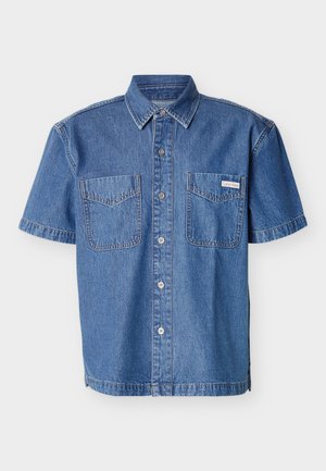 Short-sleeve denim shirt with button front, two chest pockets, and a small Calvin Klein label on the right pocket.