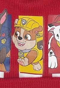 Red knit fabric featuring three character patches: a brown dog with a yellow helmet, a gray dog, and a white dog with black spots.