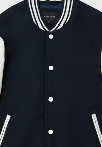 Giacca varsity in lana navy con maniche in pelle bianca, colletto a costine e bottoni a pressione bianchi. Dotata di tasche laterali con dettagli bianchi.
