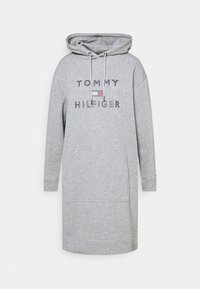 Vestido sudadera gris con mangas largas, un bolsillo frontal y capucha con cordón. Presenta el texto y el logotipo de "TOMMY HILFIGER" en la parte delantera.