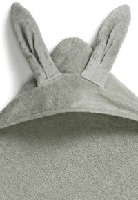 Grön huva handduk gjord av mjukt, plyschigt tyg. Har två upprätta kaninöron på huvan. Texturerad yta och enkel design.