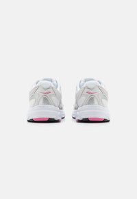Scarpe da ginnastica bianche con accenti rosa, dotate di una parte superiore in rete, suola resistente e tacco imbottito. Il design include accenti curvi e modelli texturizzati.