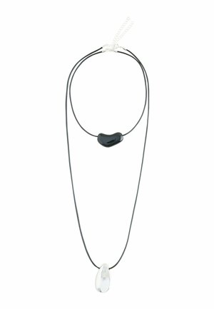 Doppellagige Halskette aus schwarzer Schnur mit einer glänzenden schwarzen unregelmäßigen Perle auf der kürzeren Lage und einem klaren tropfenförmigen Anhänger auf der längeren Lage.