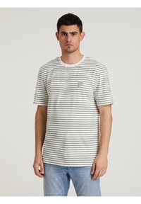 Maglietta a righe in bianco e verde scuro, realizzata in cotone. Presenta un colletto girocollo e una piccola etichetta verde con il logo sul lato sinistro del petto.