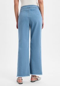 Jean large à taille haute de couleur bleu clair avec ourlet effiloché, en denim, avec poches arrière et ceinture lisse.