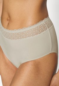 Light beige high-waisted underwear with a scalloped lace band. Smooth texture with subtle sheen, offering full coverage and a seamless design.