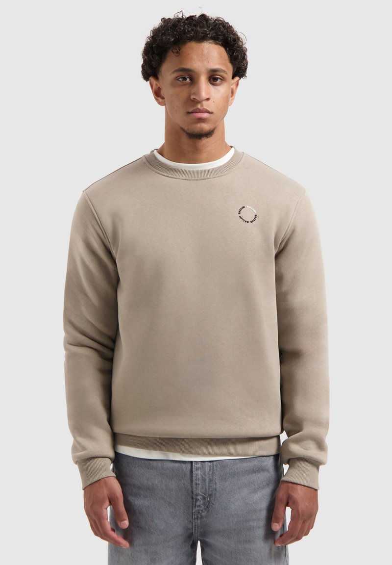 Licht beige sweatshirt met een ronde hals, ribbelmanchetten en -zoom. Voorzien van een cirkelvormig logodesign op de borst. Soepele stoftextuur.