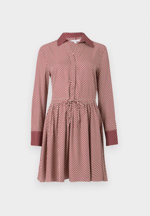 Rode jurk met witte stippen, lange mouwen, een knoopsluiting aan de voorkant en een taille met trekkoord. Heeft contrasterende details aan de kraag en manchetten.