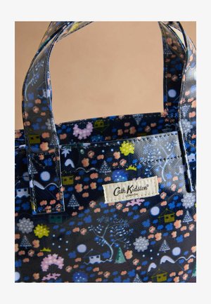 Digitalna torba z dnom z dark modrim vzorcem in barvitimi cvetličnimi in geometrijskimi motivi, črnimi ročaji in tkano oznako z logotipom.