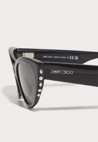 Black sunglasses with a thick frame, featuring silver studs and pearl accents on the temples, marked with "JIMMY CHOO" and "MADE IN ITALY."