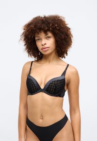 Sutien preto com copas almofadadas, apresentando um padrão pied-de-poule e acabamentos suaves. Alças ajustáveis e um design sem costuras proporcionam suporte.